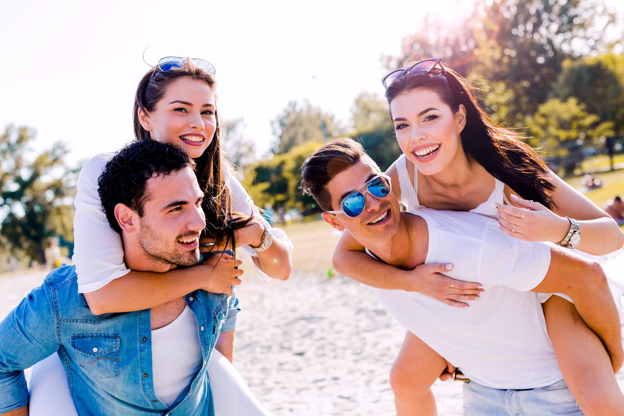 Group of young happy people carrying women on a sandy beach